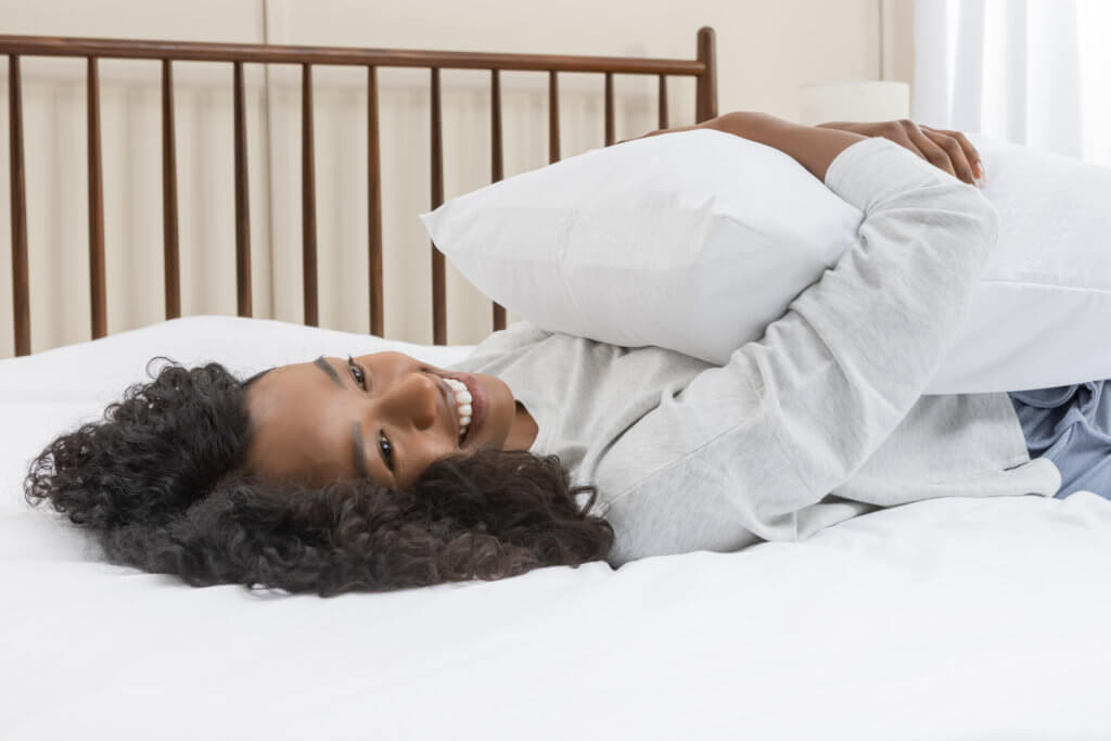 Woman smiling and hugging her pillow fitted with a pillow protector