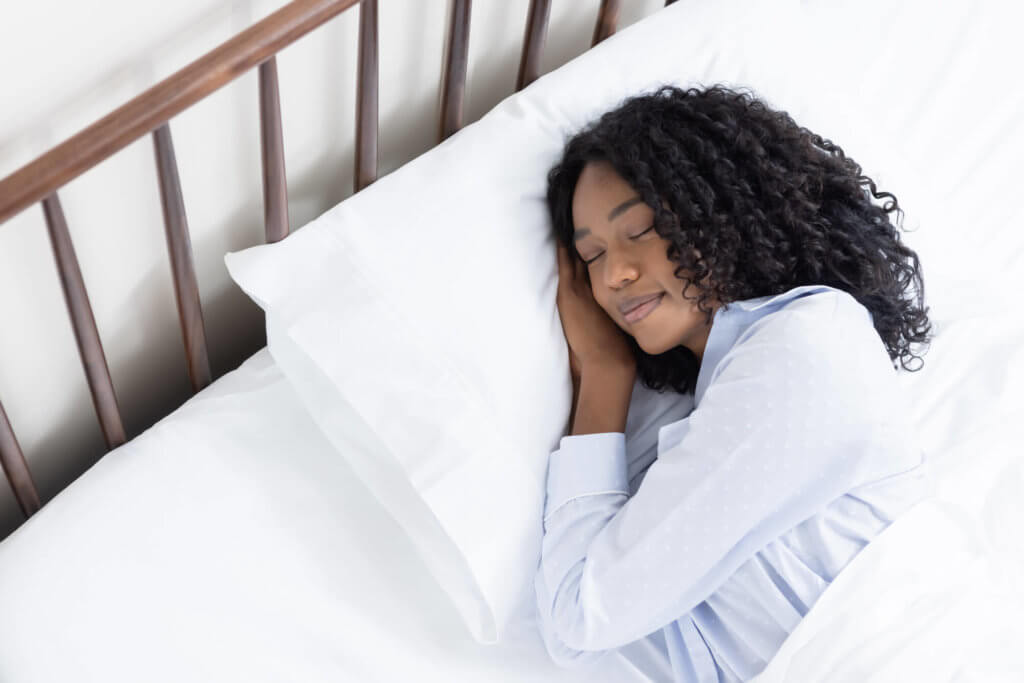 Woman peacefully sleeping in bed with her sateen cotton sheets