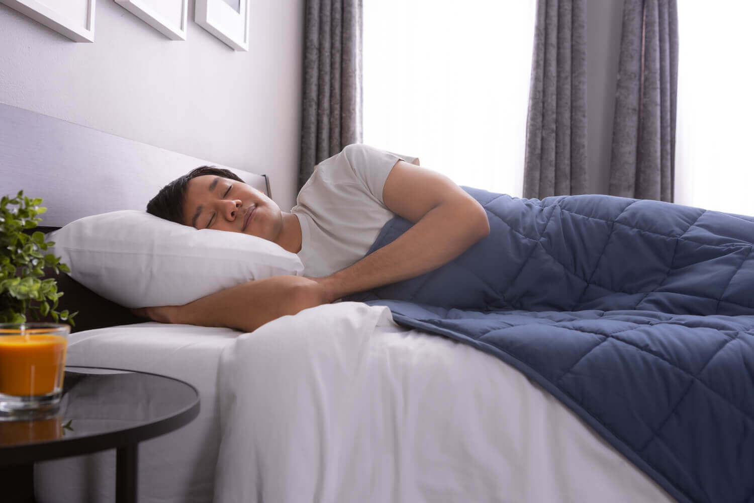 Un homme repose paisiblement dans son lit, avec une couverture lestée étendue sur son corps.