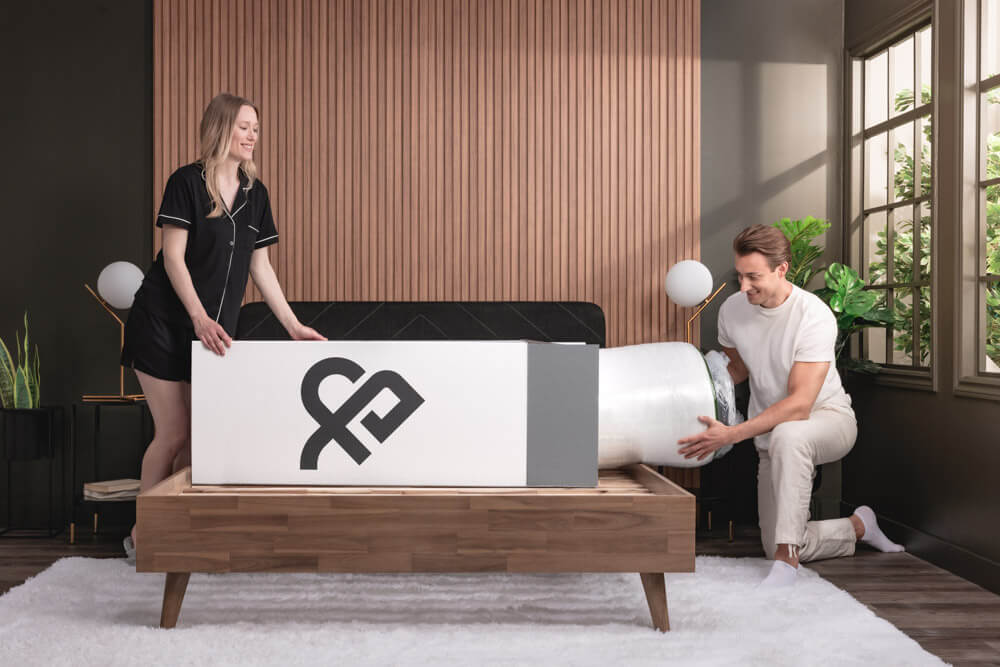 A couple happily unboxing a Logan & Cove mattress