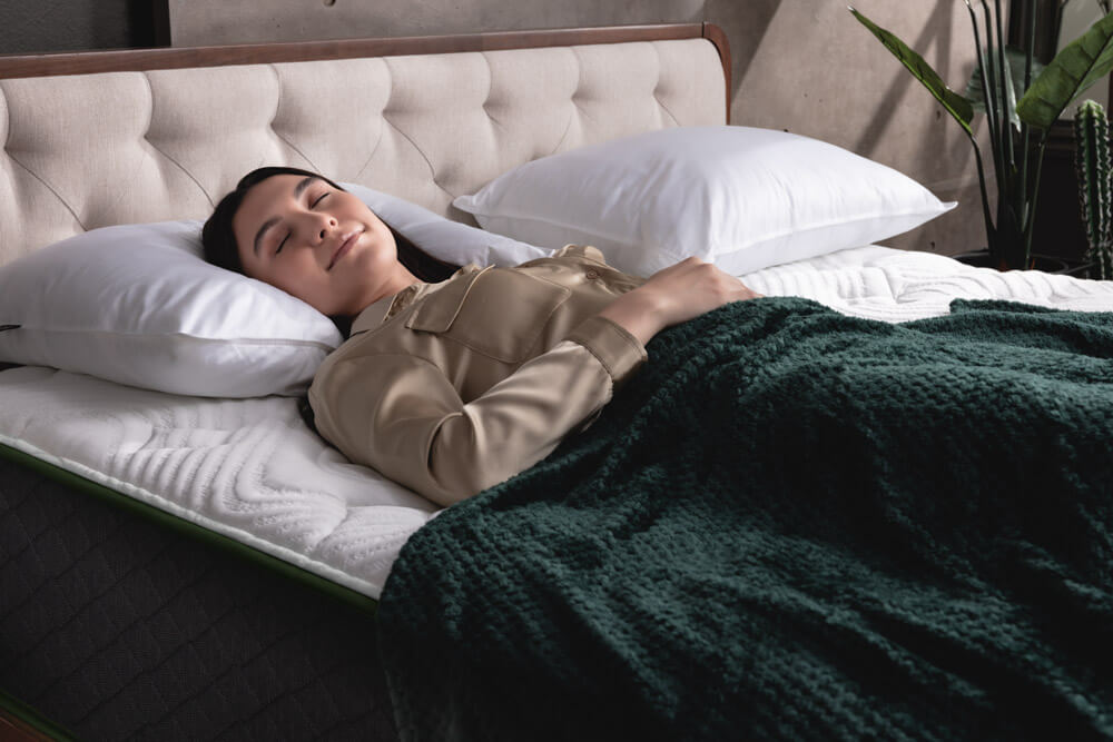 Une femme étendue sur le ventre étreint son oreiller en duvet synthétique Logan & Cove.