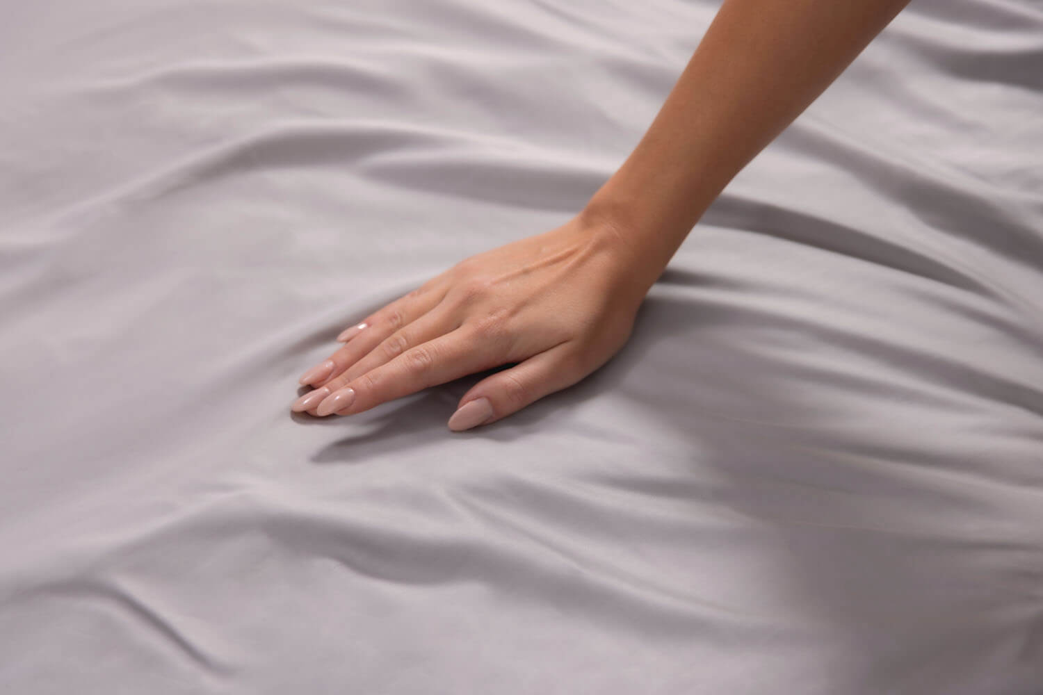 Woman sleeping peacefully, with a Light Grey set of Logan & Cove Bamboo Sheets