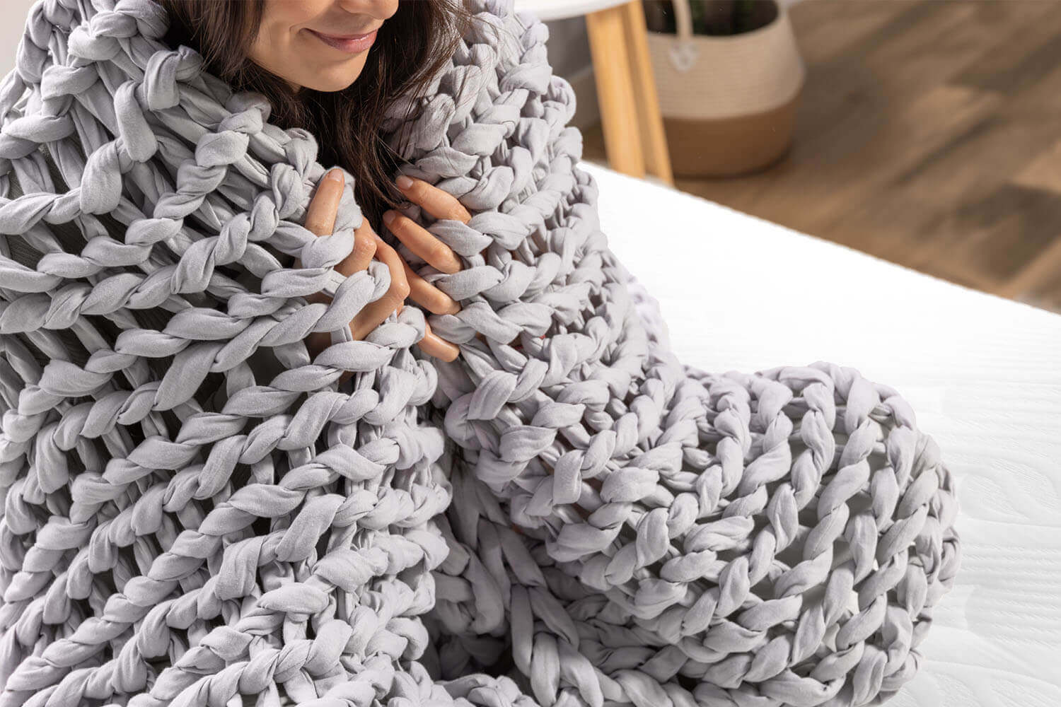 Woman snuggles the Douglas Hand Knit Weighted Blanket around her shoulders