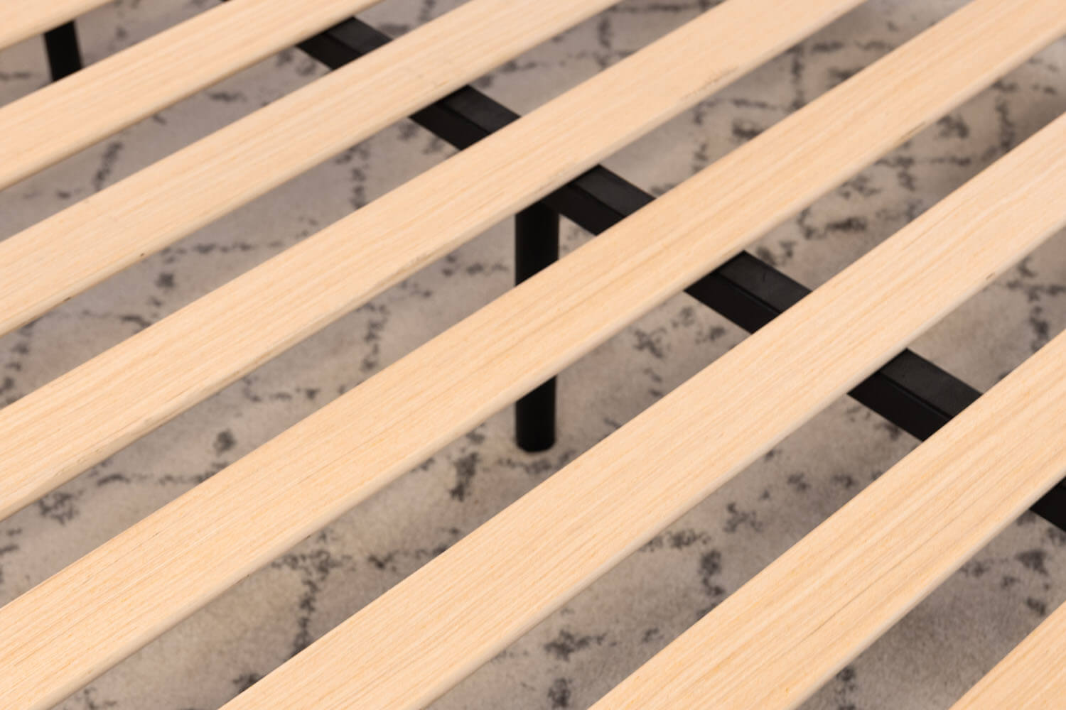 Vue détaillée des lattes de bois et de la poutre centrale en acier de la base de lit plateforme.