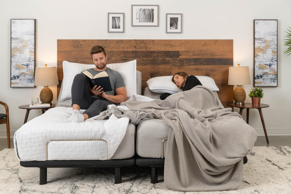 A man quietly reads while a woman reclines peacefully in their Podium adjustable bed